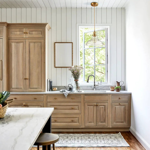 Modern Brass Pendant Light For Kitchen Island With Hand Blown Glass Shade over wooden kitchen cabinetry
