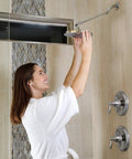 Woman adjusting Adjustable Brass Shower Arm Extension With Chrome Finish For Standard Showers 11 Inch Plus Height And Angle Control