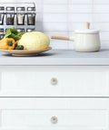 White Daisy Cabinet Knobs 4 Pack 35mm Round Drawer Pulls for Kitchen Cabinets Dressers Cupboards Wardrobes with food items on counter