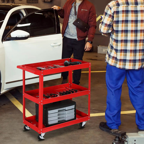 Beefy 3 Tier Rolling Tool Cart With 330 Lbs Capacity On Wheels For Garage Workshop Warehouse And Repair Shop Red Finish Durable Powder Coated Steel With Smooth Rolling Casters in use by mechanics near a white car.