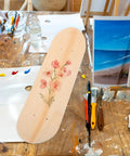 Blank Unfinished 7 Ply Wooden Skateboard Deck With Double Tail For Art Painting And Do It Yourself DIY Custom Builds Replacement Deck For Home Decor And Creative Projects on table with painting tools and floral art.