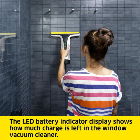 Kärcher WV 6 electric window vacuum squeegee held by person, 11-inch head, cleaning dark tile shower wall.