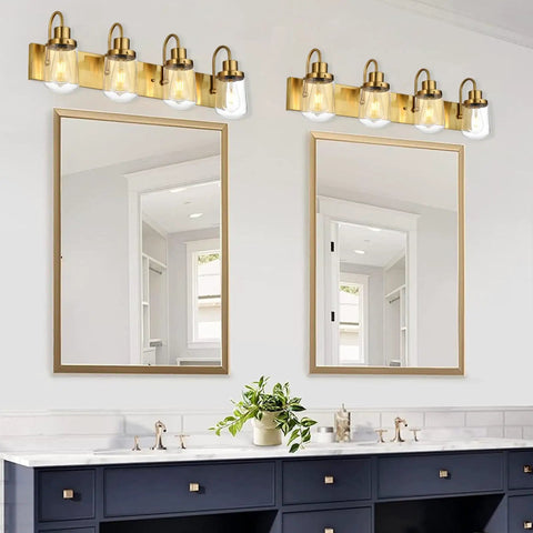 4 Light Vanity Light in painted gold finish with clear glass shades, farmhouse style wall lamp fixture above mirrors in bathroom.