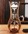Top Shelf Portable Cold Brew Drip Tower And Iced Coffee Maker With Dual Adjustable High Borosilicate Glass Valves For Custom Flow and Smooth Batch Sipping, showing wooden structure and glass components.