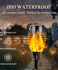 Image of 12-Pack Solar Christmas Lights Outdoor With Flickering Flame Tiki Torches Waterproof Garden Lights in the rain, highlighting IP65 waterproof feature.