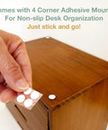 Hand placing adhesive mount on a dark mahogany cupboard for stability