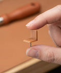 Close-up of a hand holding a brown tack in slider from Universal L Shape Drawer Glides Kit 50 Pieces Tack In Drawer Sliders For Furniture