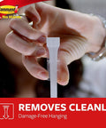 Hand removing adhesive strip from Ten Pound Extra Large Heavyweight Wall Hooks With Adhesive Strips Two Hooks And Six Strips No Drill No Mess Damage Free Mounting For Easy Home Organization And Storage Heavy Duty Hanging Solution For Kitchen Garage Office