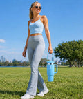 Woman in activewear holding a blue 40 Oz Double Wall Insulated Travel Tumbler With Detachable Paracord Handle And Leakproof Lid.