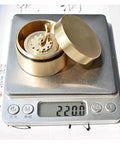 Top Shelf Vintage Brass Mini Tape Measure With Retractable Sewing Ruler showing compact design on a digital scale.