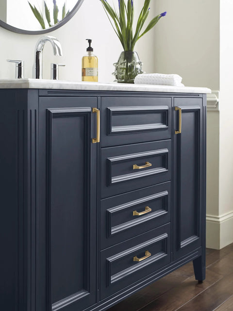 Vanity with Mulholland Champagne Bronze Cabinet Pull 5-1/16 Inch Center to Center Drawer Handle installed on dark blue cabinets.
