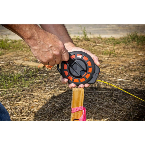 Person using Three Eighths Inch By One Hundred Foot Construction Steel Long Tape Measure Pro Grade with seated handle outdoors