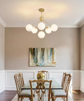 Dining room with Six Light Frosted White Glass Globe Sputnik Chandelier in Modern Gold Finish, mid-century style above table.