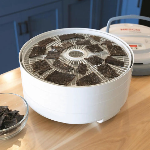 Digital Food Dehydrator With Smooth Adjustable Temperature And Even Heating For Whipping Up Homemade Beef Jerky Dried Fruit Fresh Herbs And Crispy Snacks On Four Stackable Trays In A Sleek Gray Design showing beef jerky on top tray.