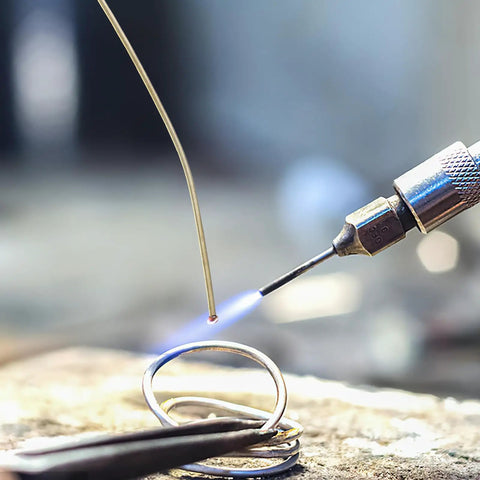 Close-up of Top Tier Copper Welding Rods Kit 4pcs For Jewelry Making, soldering wire being heated with a torch.