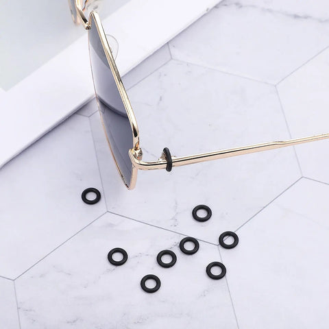 Close-up of sunglasses with 60 Pcs Eyeglass Hinge Tighteners And Repair Kit, silicone rings shown on marble surface.