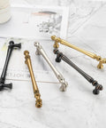 Assorted metal cabinet handles on marble surface showcasing vintage, brass, bronze, and black finishes.