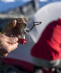 Holding PocketRocket 2 Ultralight Camping Stove Kit for Solo Backpackers with tent in background