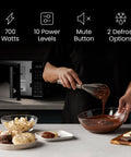 User whisking melted chocolate in a glass bowl beside No Sweat Compact Countertop Microwave Oven 0.7 Cubic Foot 700 Watts.