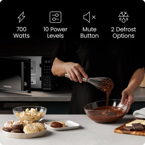 User whisking melted chocolate in a glass bowl beside No Sweat Compact Countertop Microwave Oven 0.7 Cubic Foot 700 Watts.