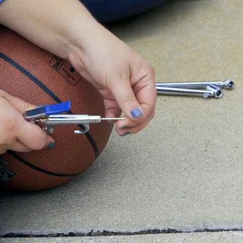 Person using blow gun from 17 Piece Compressor Inflation Kit With Blow Gun, Air Chucks And Inflation Needles on a basketball