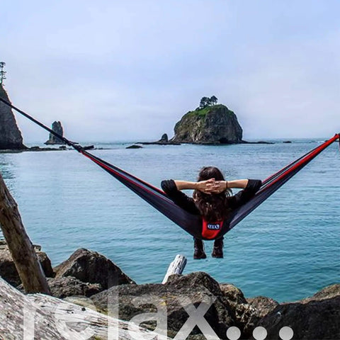 Person relaxing in hammock by water using Atlas XL Hammock Suspension System With Wide Tree Straps For Tree Protection No Knots