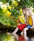 Two Pack Kid Friendly Fishing Pole Kit With Portable Telescopic Rod being used by two young girls at a pond