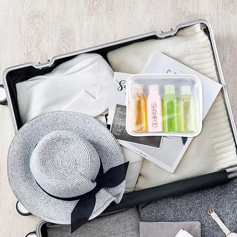 Leakproof Travel Bottles 4 Pack 3.4 Oz TSA Approved Squeeze Containers in suitcase with hat and clothes