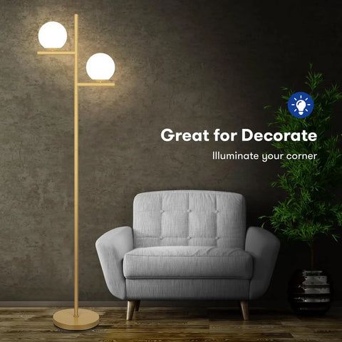 2 Globe Modern Floor Lamp With Foot Pedal Frosted Glass Shades Brass Gold Finish next to gray armchair in living room.