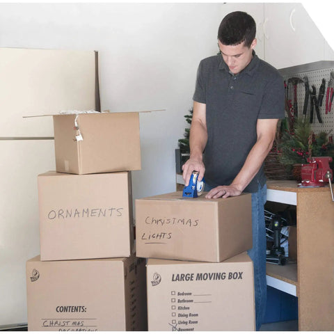 Person sealing storage boxes with High Performance Clear Packing Tape Refills, 8 Rolls Of HP260 Heavy Duty Packaging Tape in garage.