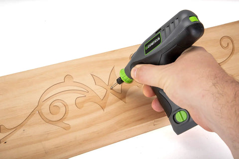 Hand using Genesis 8V Variable Speed Rotary Tool Kit for intricate wood carving on a wooden board.