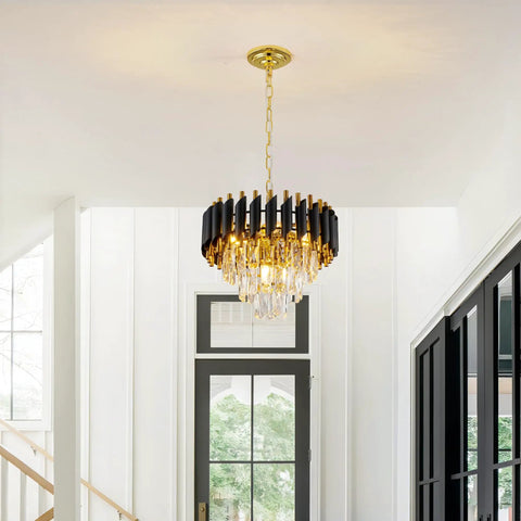 Black and gold chandelier with teardrop crystals hanging in a bright modern room