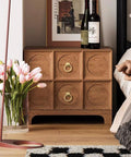 Wooden side table with built-in gold ring pulls under framed artwork, beside pink tulips and wine bottles