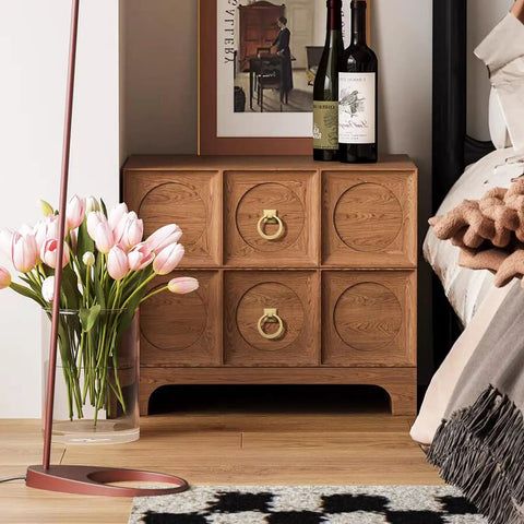 Wooden side table with built-in gold ring pulls under framed artwork, beside pink tulips and wine bottles