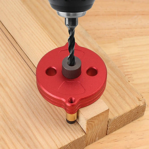 Self Centering Dowel Jig With Swap In Bushings For Knockout Precision Portable Guide Tool on wood with drill bit, showcasing red aluminum design.