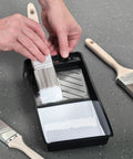 Hands using 4 Inch Paint Tray Pan Set 12 Pack Black Spill Resistant Mini Trays With Dual Wells For Rollers And Roller Pan Disposable DIY Home Improvement Project Supplies
