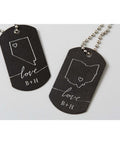Two engraved black dog tags on silver ball chains with white love script, heart outlines, and initials B+H