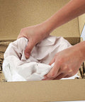 Hands placing White Newsprint Packing Paper 50 Sheets For Wrapping And Cushioning Fragile Items Perfect For Moving Shipping Handling And Small Business