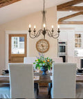 Brown Rust Metal Finish 5 Light Farmhouse Chandelier For Dining Room, Rustic Modern Industrial Style With Edison Candelabra Bulbs, 28 Inch Diameter hangs above a dining table in a rustic kitchen.