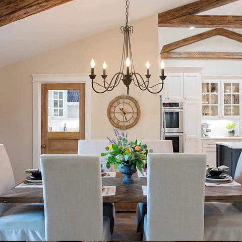 Brown Rust Metal Finish 5 Light Farmhouse Chandelier For Dining Room, Rustic Modern Industrial Style With Edison Candelabra Bulbs, 28 Inch Diameter hangs above a dining table in a rustic kitchen.