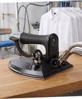 Industrial Grade Steam Iron With Precision Temperature Control For Bulk Loads And Dry Cleaning Factories, Metal Body, Fast Heat, Heavy Duty Performance, Pressing Table Ready, Built For Repeated Commercial Use, black metal base on table
