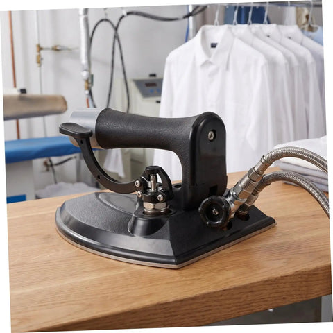 Industrial Grade Steam Iron With Precision Temperature Control For Bulk Loads And Dry Cleaning Factories, Metal Body, Fast Heat, Heavy Duty Performance, Pressing Table Ready, Built For Repeated Commercial Use, black metal base on table