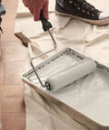 Person using a paint roller on a tray, preparing to paint with 2 Gallon Metal Paint Grid Pack Of 24 For DIY Painters Expanded Wire With Reinforced Edges Flat Design That Fits 2 Gallon Buckets Heavy Duty Paint Grid For Smooth Even Coverage And Quick Cleanups.