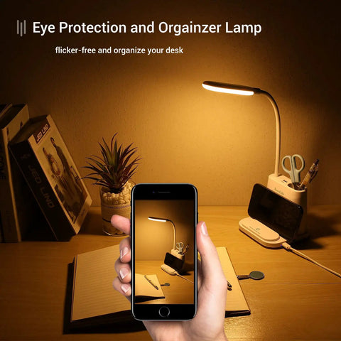Must Have LED Desk Lamp With USB Charging Port, Pen Holder And Phone Holder, on a desk with plant and books