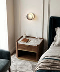 Modern Round LED Wall Sconce, 8W Smoke Grey Striped Glass Vanity Light above a stylish nightstand next to elegant bedding.