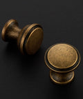 Close-up of two 20 Pack Antique Brass Cabinet Knobs 1-1/4 Inch Round Drawer Handles with Fingerprint Resistant Swanky Finish.