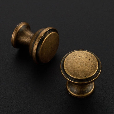 Close-up of two 20 Pack Antique Brass Cabinet Knobs 1-1/4 Inch Round Drawer Handles with Fingerprint Resistant Swanky Finish.