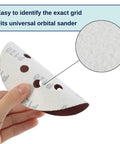 Hand holding one disc from Five Inch 8 Hole Sanding Discs Set, 30 Pack with Assorted Grits, showing fit for universal orbital sander.