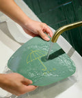 Hair Stopper Shower Drain Strainers Silicone Adjustable, A held over sink while water flows through it, demonstrating its use.