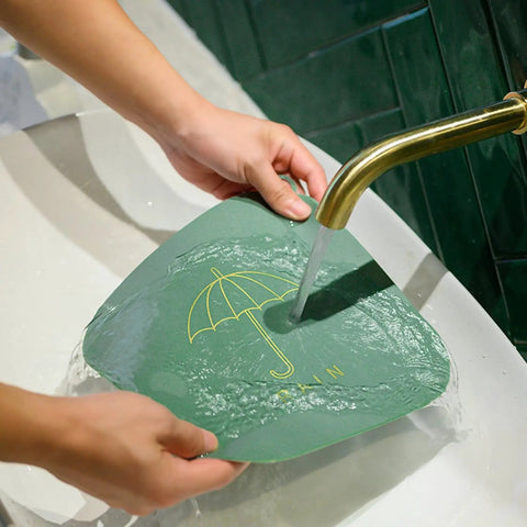 Hair Stopper Shower Drain Strainers Silicone Adjustable, A held over sink while water flows through it, demonstrating its use.